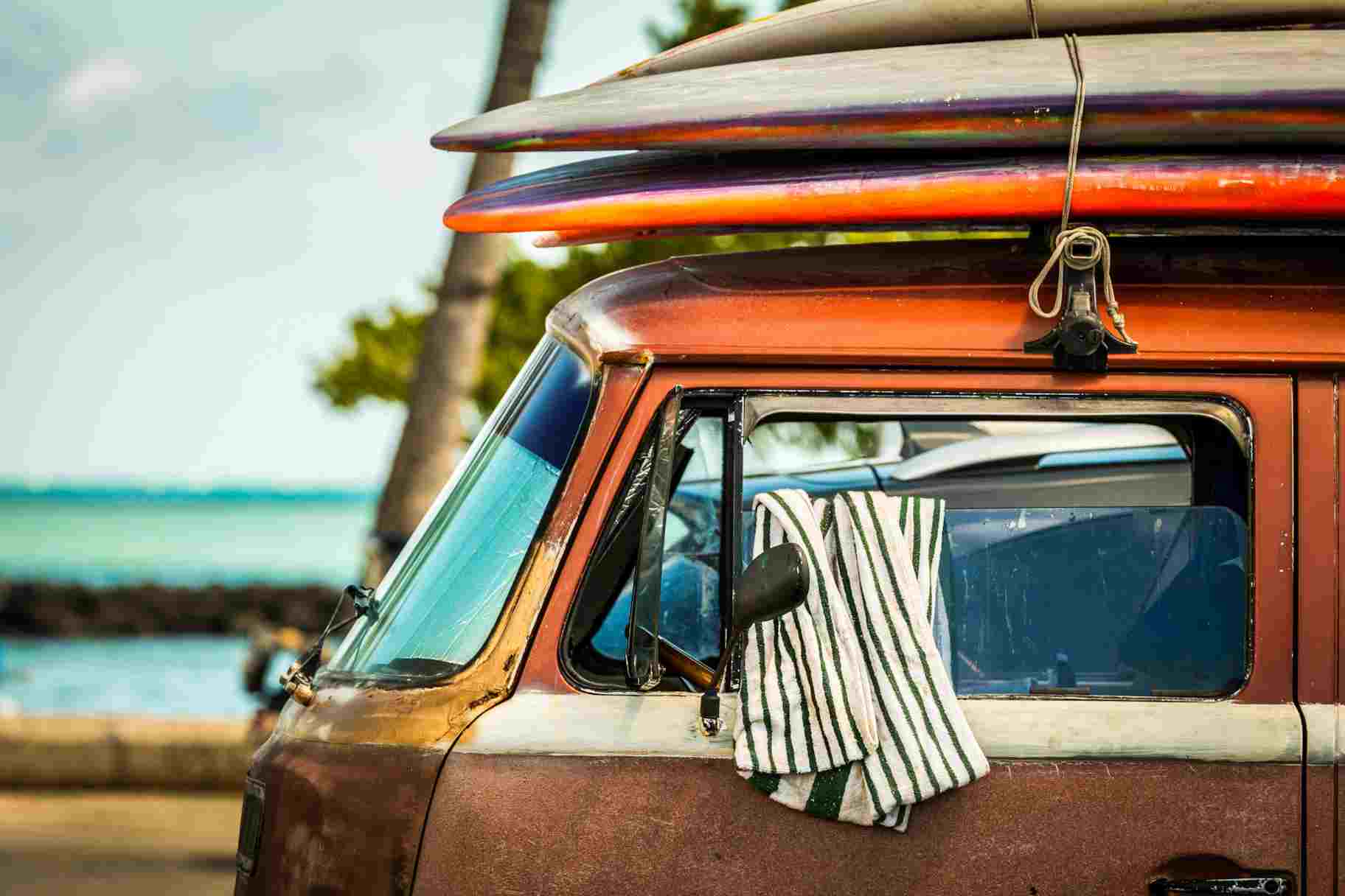 Vintage vehicle with surfboards attached to the top.